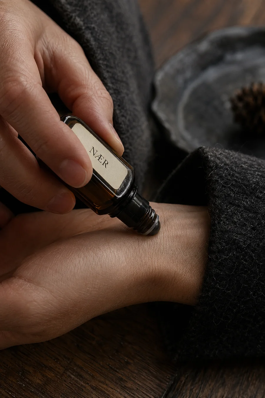 Applying NÆR fragrance oil to wrist near wool coat cuff